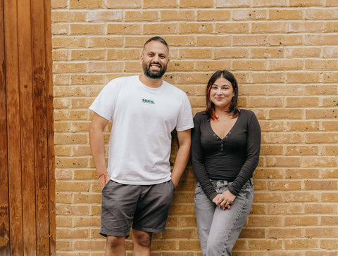 SOKA's founders, uncle-and-niece duo Milan and Ashni, smiling and leaning against a wall.
