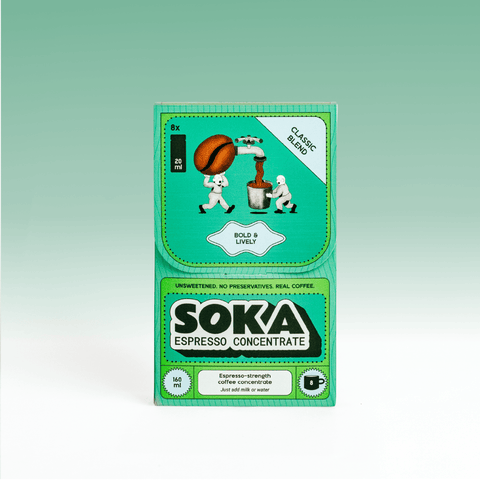 A package of SOKA Espresso Concentrate coffee on a light green gradient background. The packaging is primarily green with white and black text, featuring cartoon illustrations of people carrying a coffee bean.