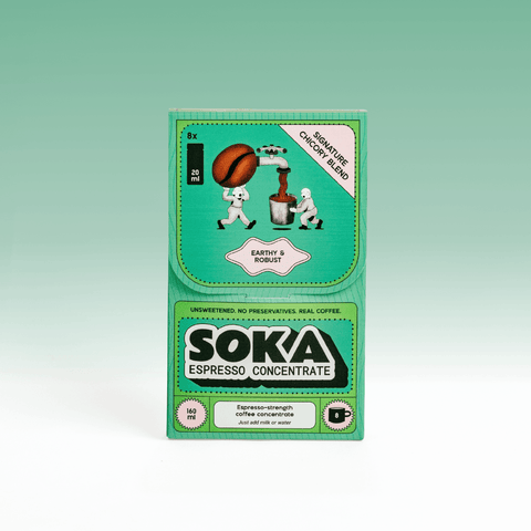 A package of SOKA Espresso Concentrate in the flavour 'SIGNATURE CHICORY BLEND', decorated with cartoon illustrations of characters playing squeezing a coffee bean into a cup, set against a light green gradient background.